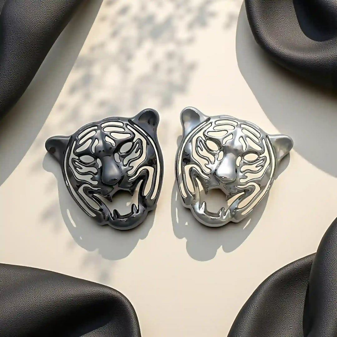 Gunmetal and silver tiger head emblems side by side on satin 