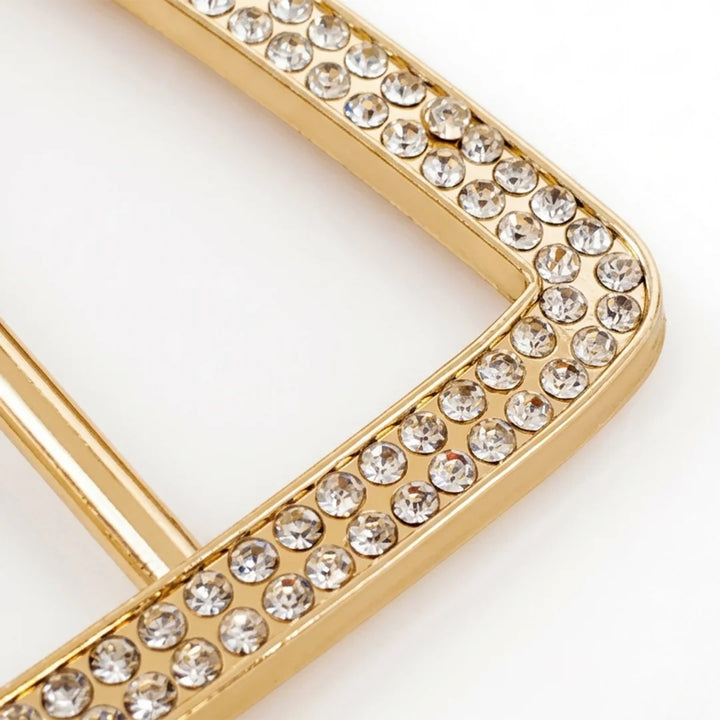 ANI Accessories close-up of trapezoid gold belt buckle corner showing double-row pave rhinestones set in polished gold metal