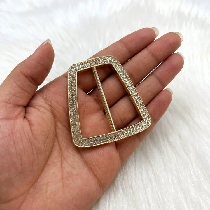 ANI Accessories trapezoid pave rhinestone gold belt buckle held in palm to show real size, on white fur background