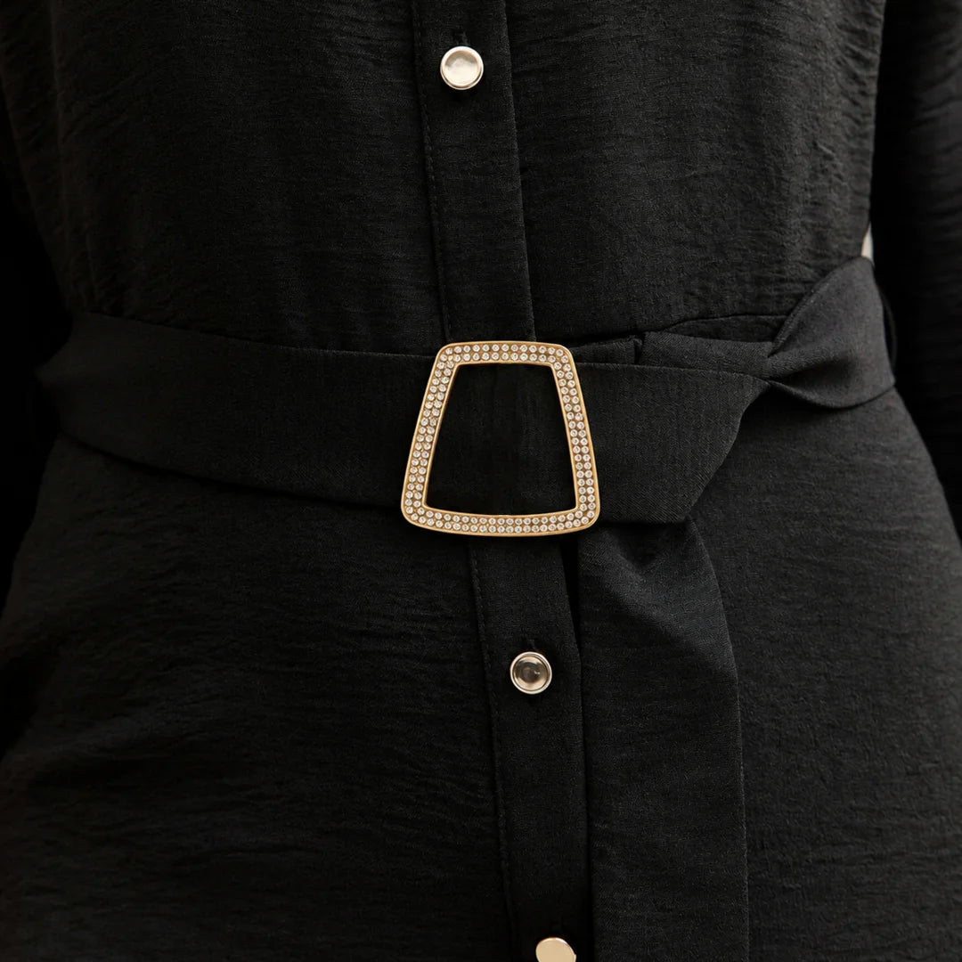 ANI Accessories trapezoid rhinestone gold buckle styled on the fabric waist belt of a black button-front shirt dress