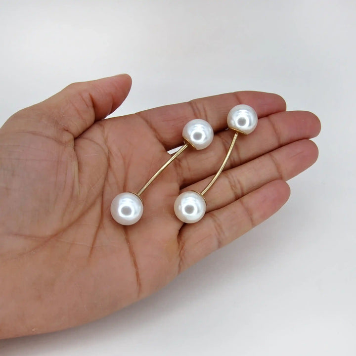 Two twin pearl pins held in hand to show their size 