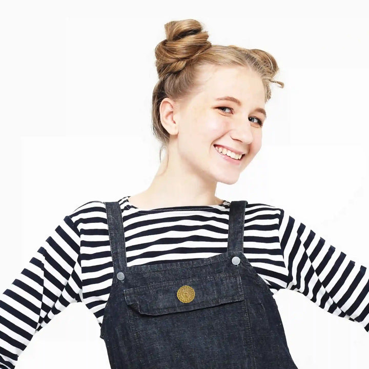 Stylish model wearing a striped top and denim overalls showcasing a lion head gold brooch