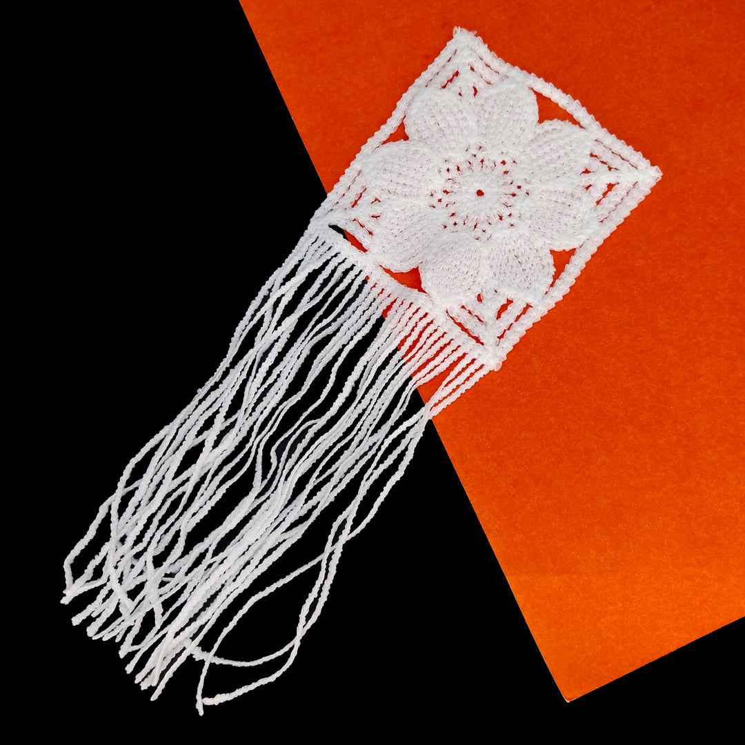 ANI Accessories white flower patch for clothing with loose fringe on a black and orange background 