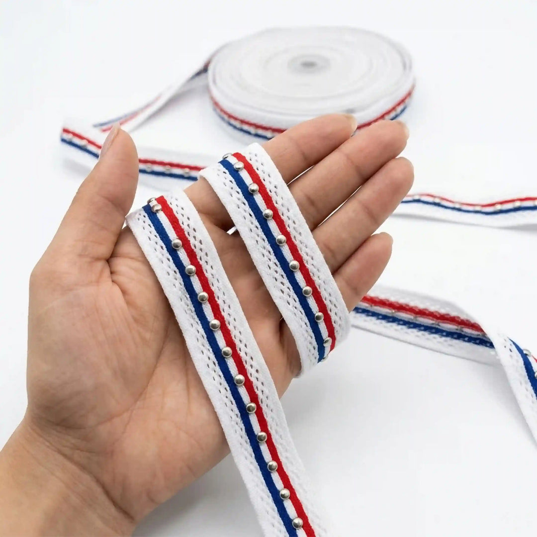 ANI Accessories white lace border with red and blue stripes held in hand next to the roll with white color background 