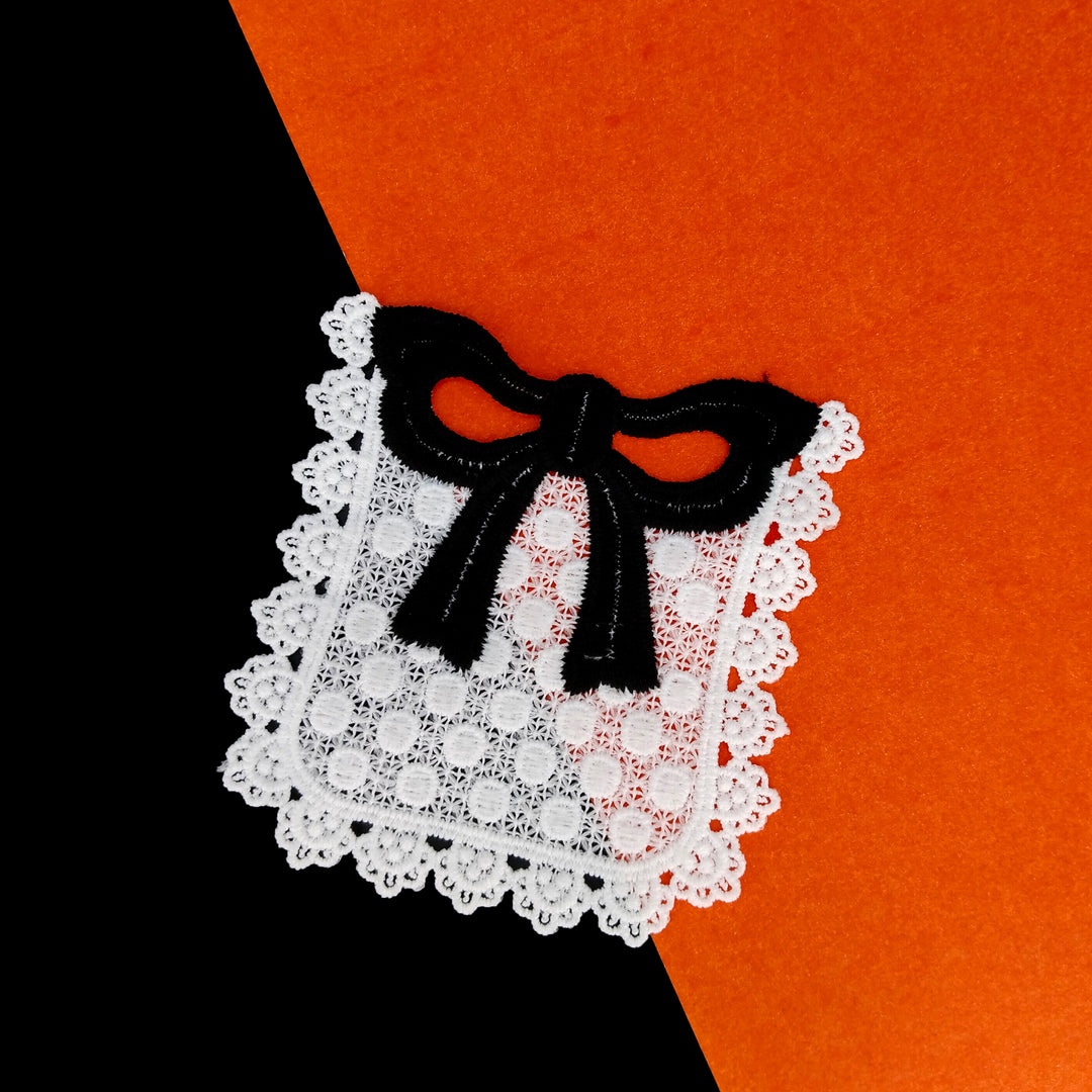 ANI Accessories white scalloped pocket patch with black bow on a black and orange background 